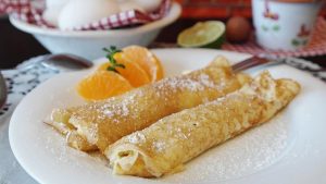 Two Crepes on Plate with Slices of Orange