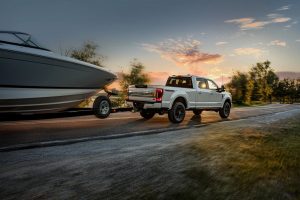 White Ford F-250 Towing Boat Down the Highway