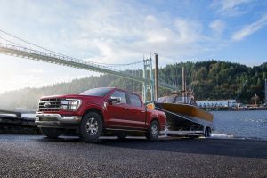 Red Ford F-150 pulling a boat on a trailer out of the dock.